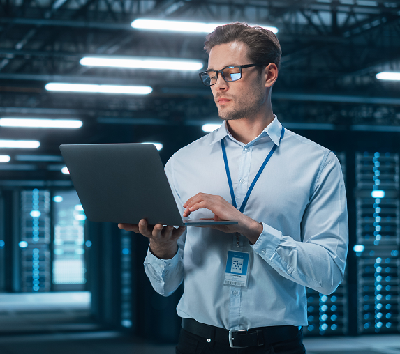 Man using laptop in a server room.